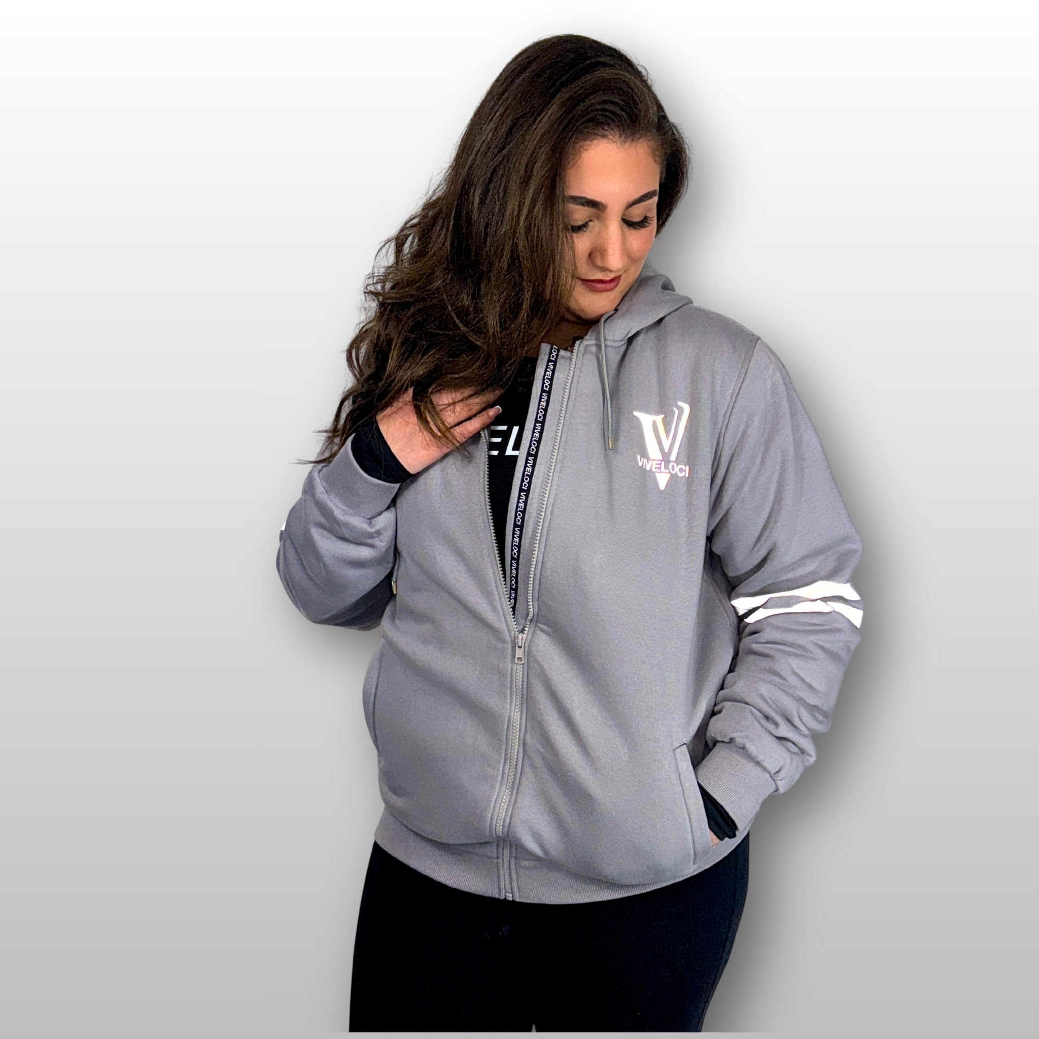 Bernadette is wearing a ViVeloci Kevlar Lined, Armored, Motorcycle Hoodie in Silver Grey.  Reflective back, front and arm bands.  Removable CE Level 1 Armor in Shoulders, Elbows and Back. Two zippered pockets on the outside and one on the inside.