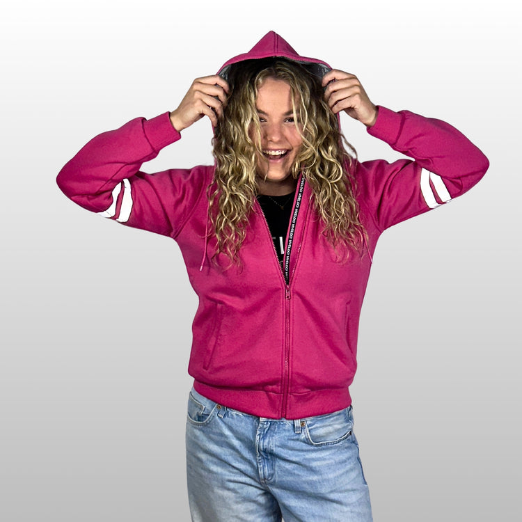 Emily is wearing a ViVeloci Kevlar Lined, Armored, Motorcycle Hoodie in Pink.  Reflective back, front and arm bands.  Removable CE Level 1 Armor in Shoulders, Elbows and Back. Two zippered pockets on the outside and one on the inside.