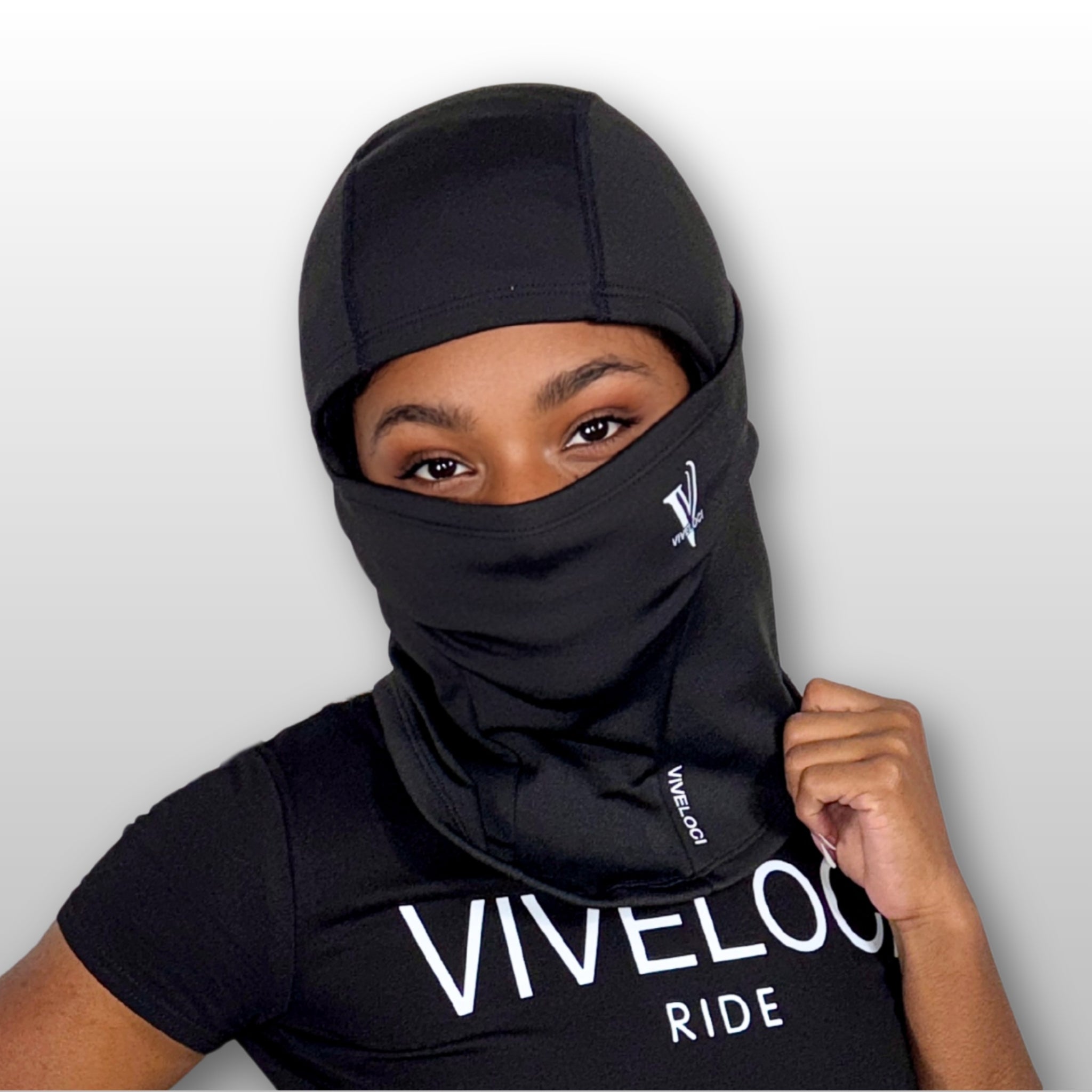 Aaliyah wearing a black balaclava and black crop to with 'VIVELOCI' branding on a light gray background