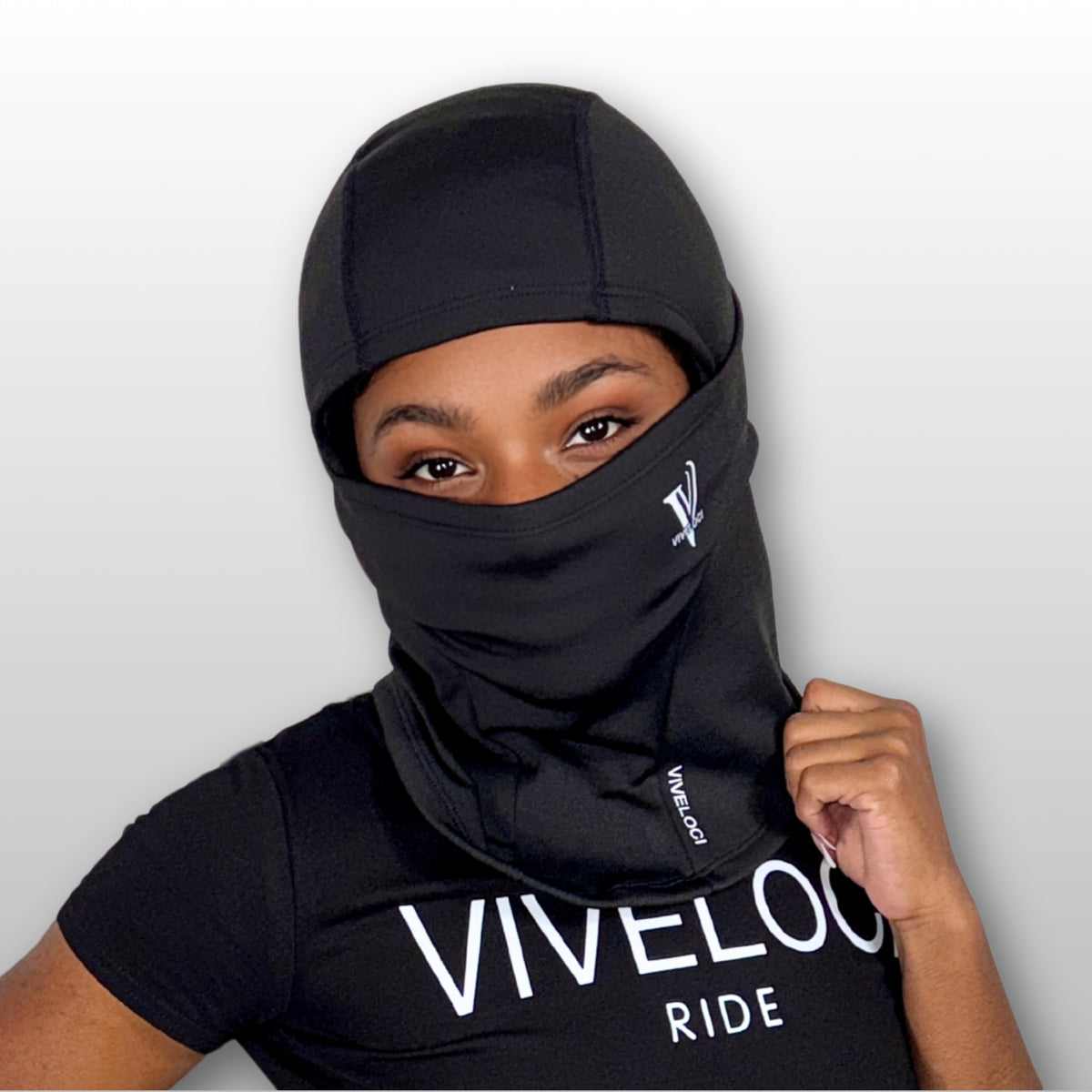 Aaliyah wearing a black balaclava and black crop to with 'VIVELOCI' branding on a light gray background