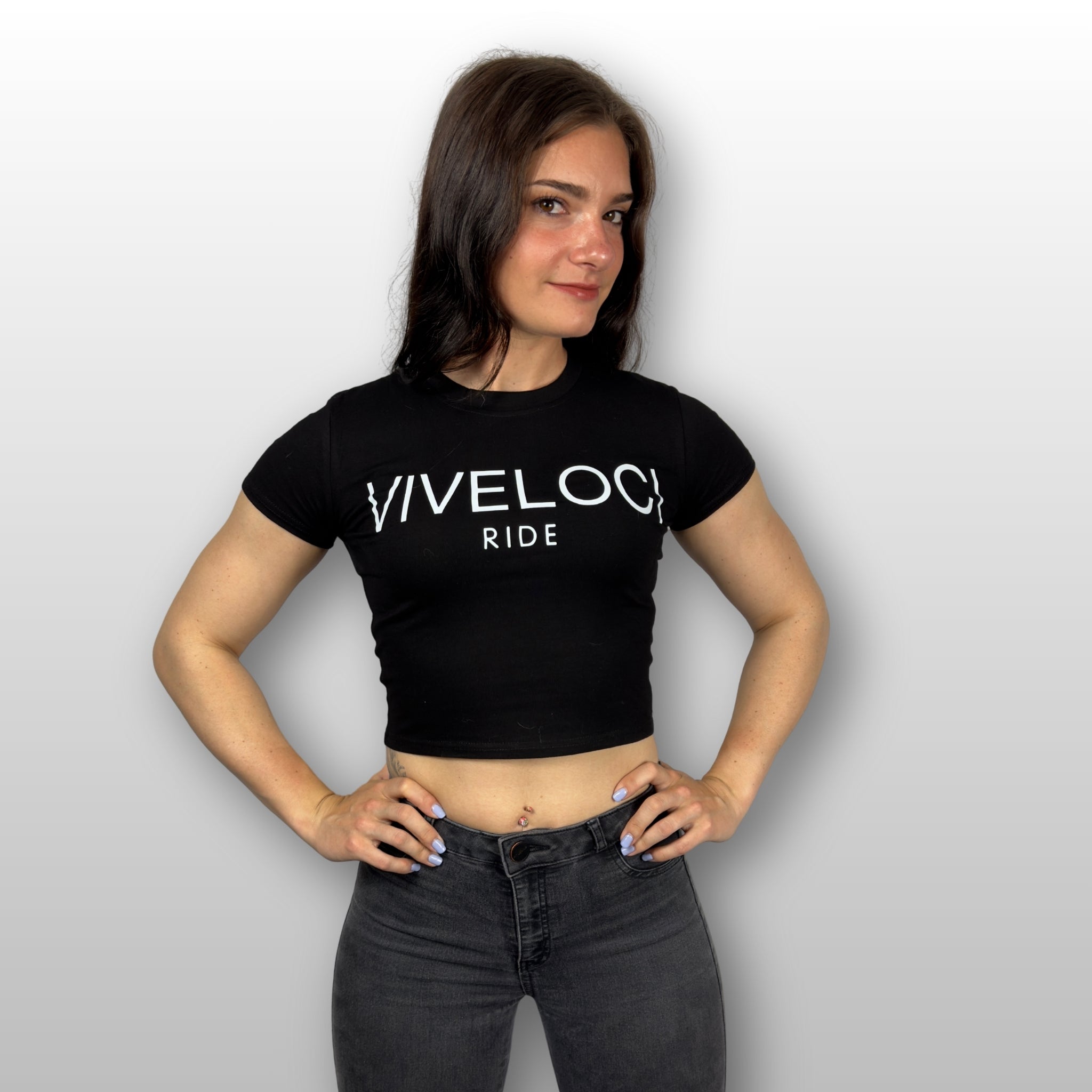 Kendra wearing a black ViVeloci RIDE short sleeved crop top against a grey background.