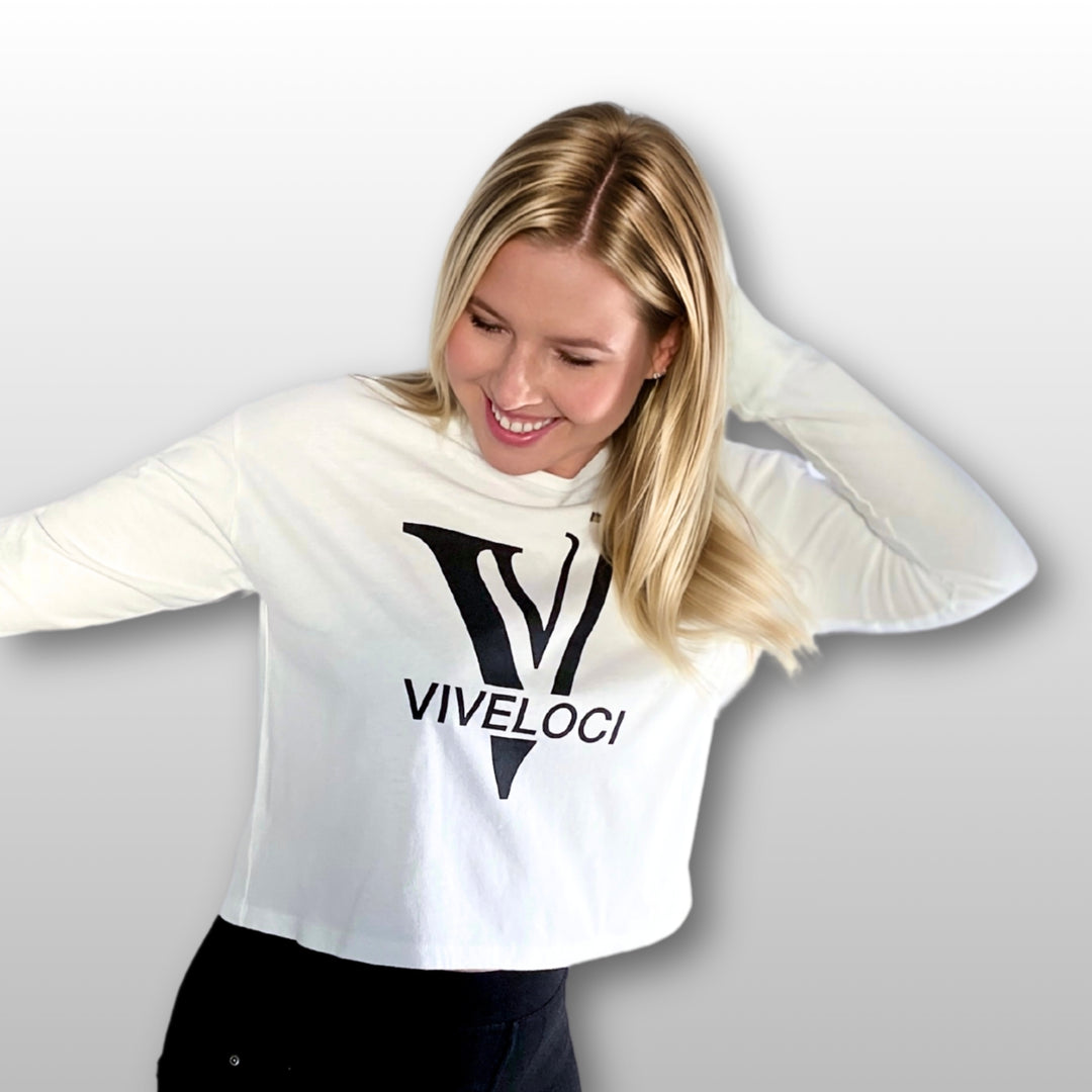 Magdalena wearing a white ViVeloci long sleeved crop top against a grey background.
