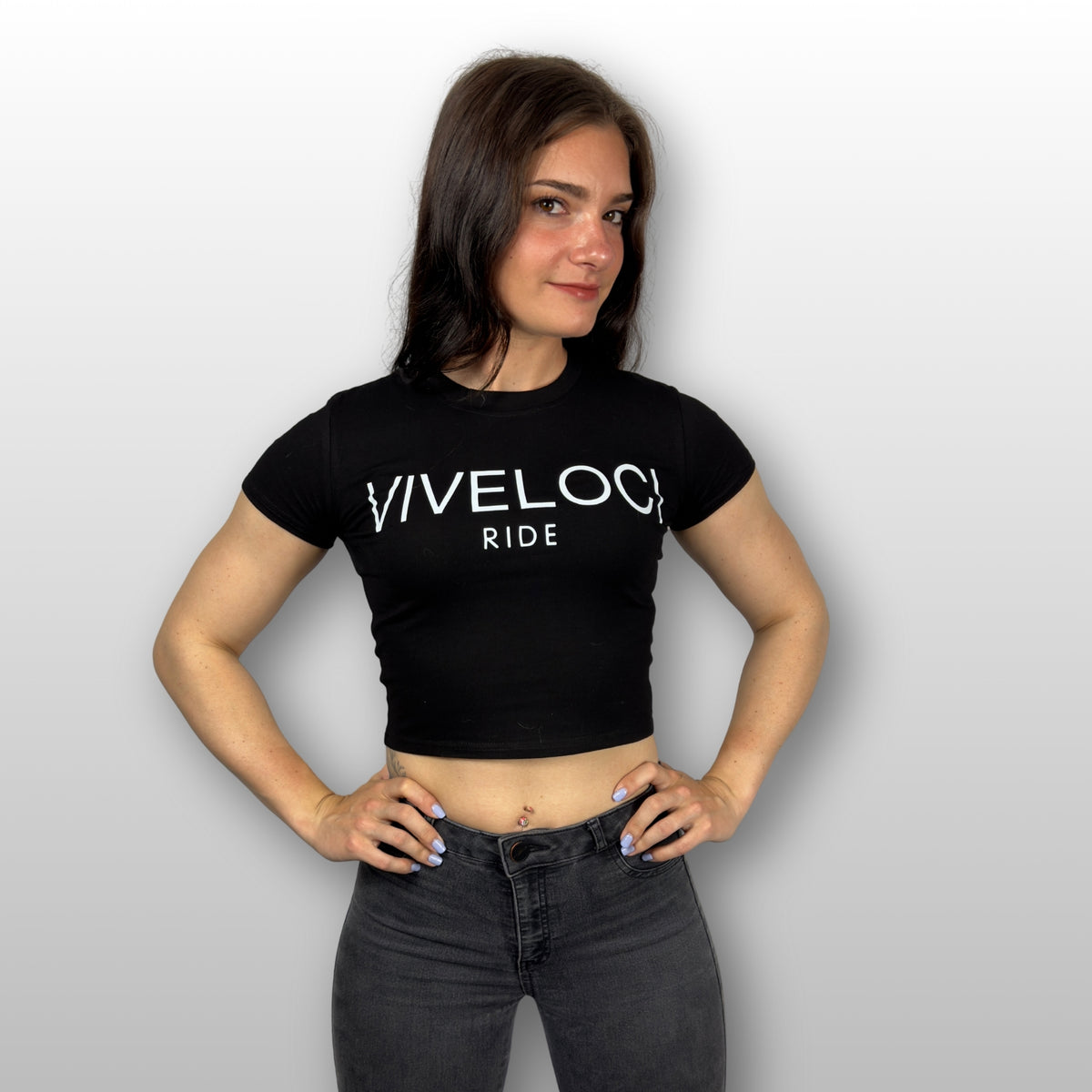 Kendra wearing a black ViVeloci RIDE short sleeved crop top against a grey background.